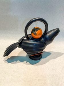 Raven shaped teapot sculpture with a persimmon on the lid